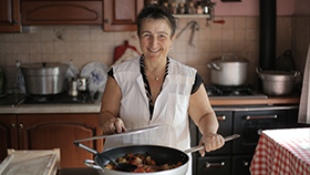 Woman in the kitchen cooking with a large pot.